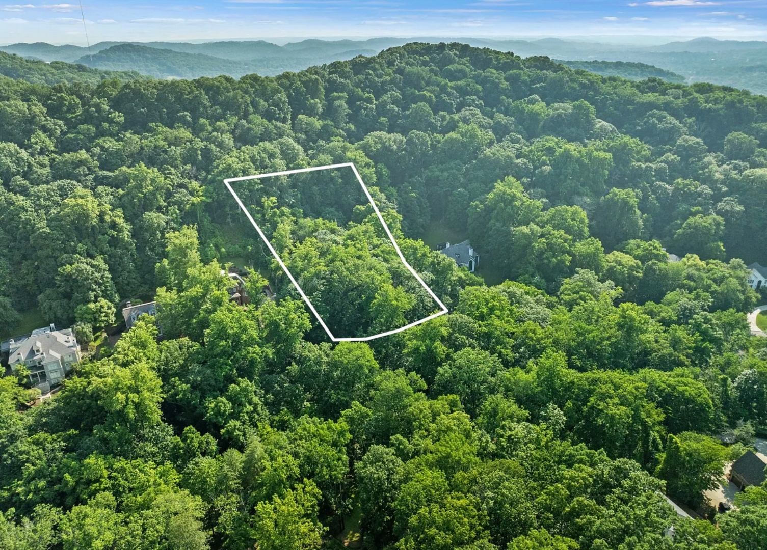 Aerial view of the 2.01-acre lot at 35 Annandale outlined among hardwoods, with the rolling Tennessee hills beyond
